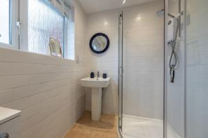 a white bathroom with a sink and a shower at 12 The Close in Brancaster +34 photos