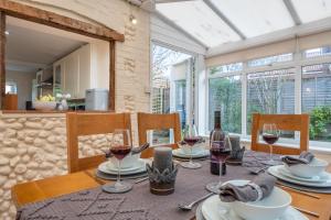 ein Esszimmer mit einem Tisch mit Weingläsern in der Unterkunft Daisy Cottage H in Holt