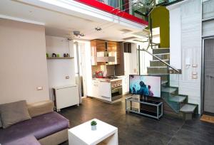 een woonkamer met een bank en een tv en een keuken bij Incantevole appartamento ristrutturato nella Darsena di Pozzuoli in Pozzuoli