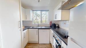 a kitchen with white cabinets and a sink and a window at 82 Strawberry Hill, Tolroy Manor in Hayle