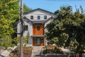 a white house with a wooden door in a yard at Chris's Sweet Suite - 84 Walkscore in Seattle