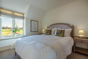 a white bedroom with a large bed and a window at Saltings House in Ringstead
