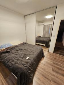 1 dormitorio con cama y espejo grande en Departamento amoblado con balcón y cochera en la entrada de escobar en Belén de Escobar