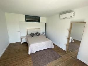 a white bedroom with a bed and a mirror at Olivo de Reis in Caldas de Reis