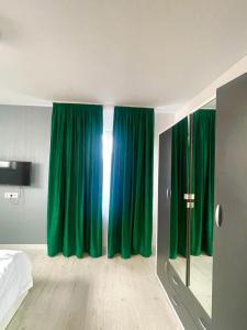 - une chambre avec des rideaux verts, un lit et un miroir dans l'établissement Residence 1, à Ploieşti