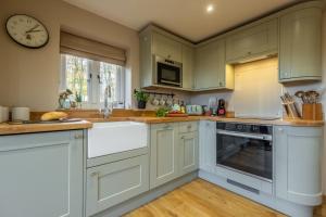 a kitchen with white cabinets and a clock on the wall at Bumblebee Cottage 