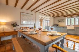 a kitchen with a large wooden table with glasses of wine at The Cart Shed NC in North Creake