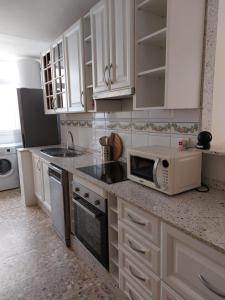 una cocina con armarios blancos y microondas en una encimera en AMPURDAN Bella Vista, en Torre del Mar