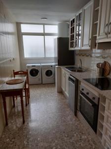 uma cozinha com um lavatório, máquinas de lavar roupa e uma mesa em AMPURDAN Bella Vista em Torre del Mar
