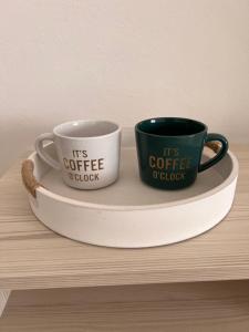 two coffee mugs sitting on a plate on a shelf at Sobe Lea in Sukošan