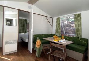 a room with a table and a green couch at Domaine Résidentiel de Plein Air Odalys Monplaisir in Saint-Trojan-les-Bains