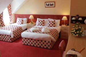 two beds in a hotel room with red carpet at Saxonville Hotel in Whitby