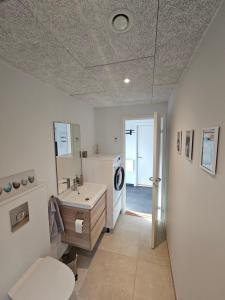a white bathroom with a sink and a toilet at Brand new apartment with stunning skyline views in Tórshavn