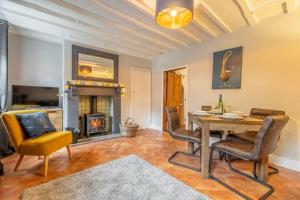 a dining room with a table and chairs and a fireplace at Teacup Cottage in Syderstone