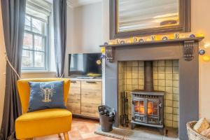 a living room with a yellow chair and a fireplace at Teacup Cottage in Syderstone