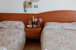 een slaapkamer met 2 bedden en een tafel met bloemen bij Hotel Villa Verde in San Mauro a Mare