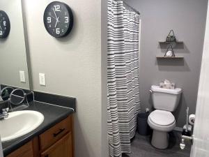 a bathroom with a toilet and a clock on the wall at Luxury Modern Condo by the Lake - Breezy Escape in Branson