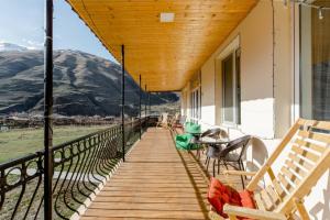 un porche con bancos, mesas y montañas al fondo en Hotel Garbani, en Kazbegi