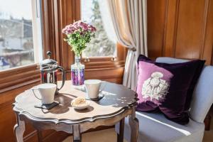 Una mesa con dos tazas y un jarrón con flores. en Strathallan Bed and Breakfast, en Grantown-on-Spey