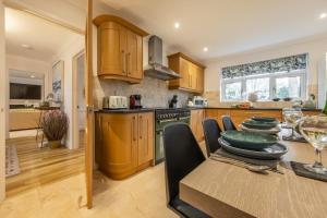 a kitchen with wooden cabinets and a table with a dining room at Harp Garden in Fakenham
