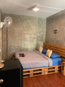 a bedroom with a bed with blue sheets and a fan at Koh Mak Homestay in Ko Mak