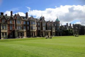 a large building with a grass field in front of it at Scouts Cottage in Snettisham