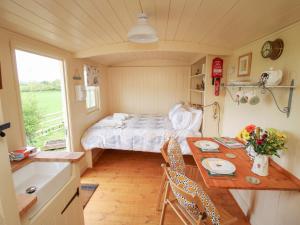 キダーミンスターにあるLe Petite Pound Houseのベッドと木製テーブル付きの小さな部屋