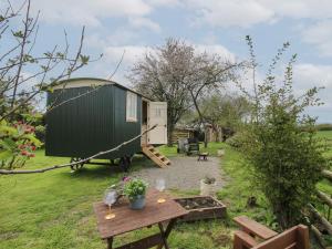a caravan conversion in a garden with a table and a bench at Le Petite Pound House in Kidderminster