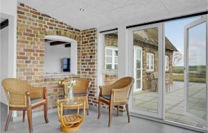 a conservatory with chairs and a brick wall at Nice Home In Tim With House A Panoramic View in Halkær