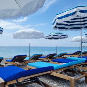 um grupo de cadeiras de praia e guarda-sóis numa praia em Haliviera - Golden Square, 1min from beach em Nice