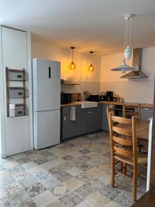 a kitchen with a white refrigerator and a table at La laiterie in Bouhet
