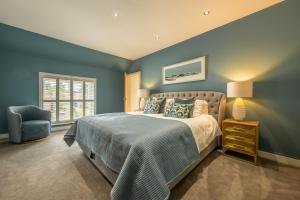 a bedroom with blue walls and a bed and a chair at Pinchen House in South Creake