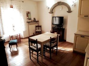 un soggiorno con tavolo, sedie e TV di Appartamento nel centro storico di Fiumalbo a Fiumalbo