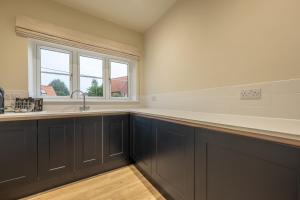 a kitchen with black cabinets and a sink and a window at Hedgerows 8 in Burnham Market