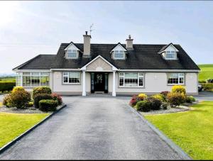 a white house with a black roof and a driveway at Green Haven V93P230 in Killarney