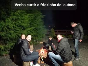 grupa ludzi siedzących w nocy przy ogniu w obiekcie Refúgio Santo Antônio w mieście Urubici
