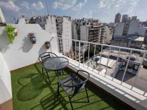 Duas cadeiras e uma mesa numa varanda com uma cidade em Hotel Impala em Buenos Aires