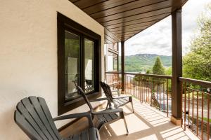 - deux chaises sur une terrasse couverte avec vue sur les montagnes dans l'établissement The Outlook over Lac -Tremblant by Instant Suites, à Mont-Tremblant