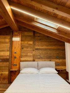 a bed in a room with wooden walls and ceilings at La Louye su La Goumba in Pontboset