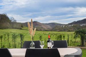 una mesa con botellas de vino y copas y un campo en Maison au cœur du Pays Basque, en Cambo-les-Bains