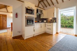 a kitchen with white cabinets and a wooden floor at The Stables in North Walsham