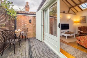 a patio with a table and chairs and a television at The Stables in North Walsham