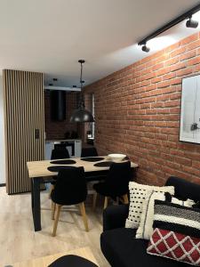 een kamer met een bakstenen muur en een tafel en stoelen bij Apartament Śródmieście in Augustów