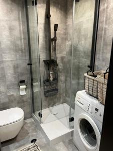 a bathroom with a washing machine and a shower at Apartament Śródmieście in Augustów +3 photos