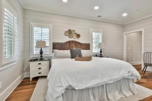 a white bedroom with a large bed and two windows at The Cottages at Laurel Brooke in Peachtree City