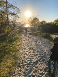 Casa Blanca في Strandbaden: شخصين وكلب يمشي على طريق ترابي