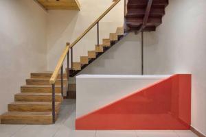 a staircase with a red and white wall and wooden stairs at Collection O Hotel Shagun Palace in Bhopal