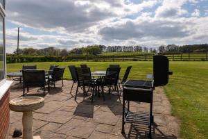 un patio avec des tables, des chaises et un champ dans l'établissement Tixall Manor Farm, à Stafford