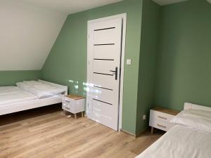 een slaapkamer met 2 bedden en groene muren bij Domek Oliwkowy Balia z Jacuzzi KASZUBY in Niesiołowice
