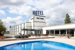 een hotel met een zwembad voor een gebouw bij Globales Post Hotel & Wellness in Herstal